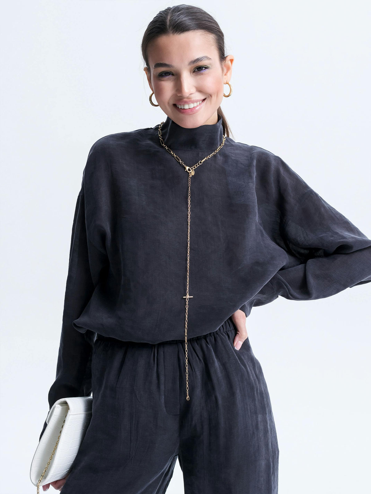 Blouse col montant noire chic avec collier doré et pantalon coordonné, look élégant et moderne