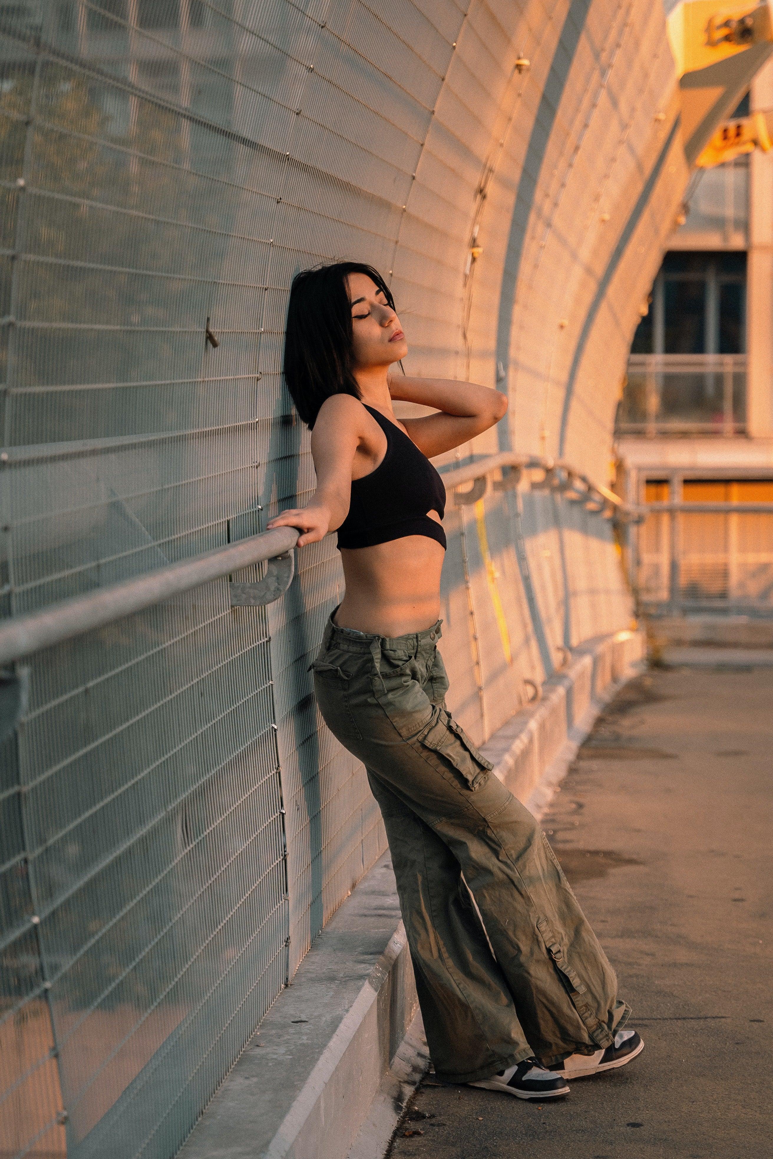 Femme en pantalon cargo vert et crop top noir, pose urbaine chic