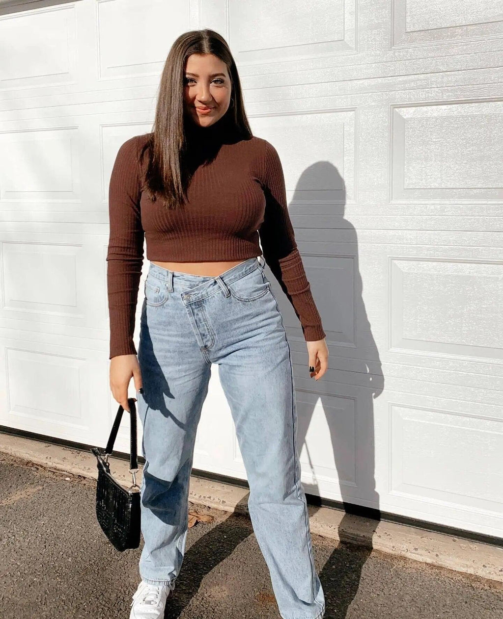 Femme en pull marron ajusté et jeans larges bleu clair, look chic et tendance